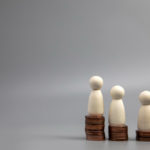 miniature people standing on coin stacks