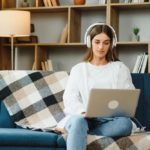 woman sitting on a couch with a laptop and headphones