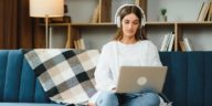 woman sitting on a couch with a laptop and headphones