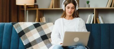woman sitting on a couch with a laptop and headphones
