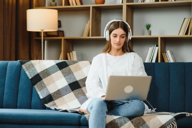 woman sitting on a couch with a laptop and headphones