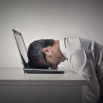 man sitting with his head on a laptop