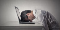 man sitting with his head on a laptop