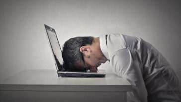 man sitting with his head on a laptop