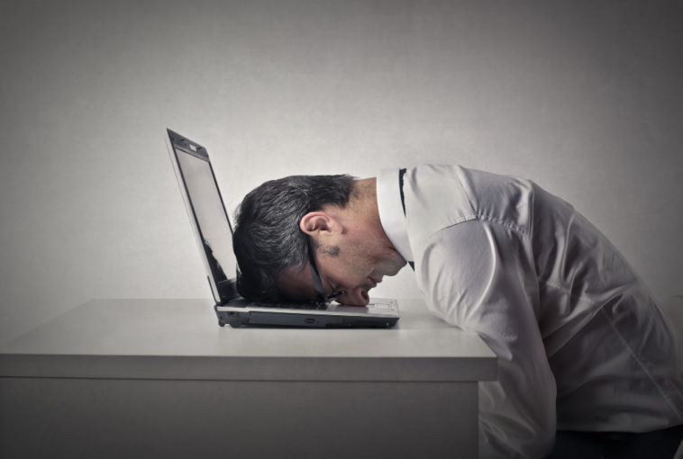 man sitting with his head on a laptop