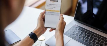 person holding a smartphone showing the amazon logo