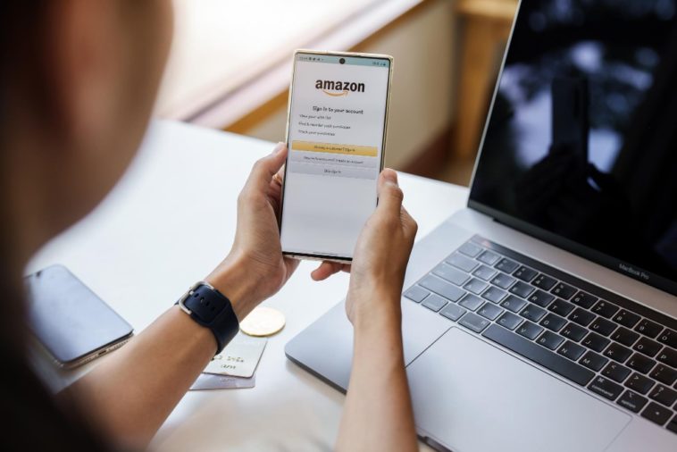 person holding a smartphone showing the amazon logo