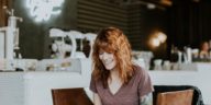 smiling woman sitting with laptop in coffee shop