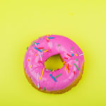 donut with pink glaze with a yellow background