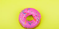 donut with pink glaze with a yellow background