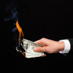 hand holding burning dollar bills