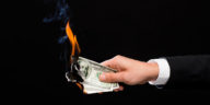 hand holding burning dollar bills