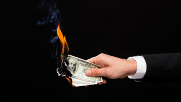 hand holding burning dollar bills