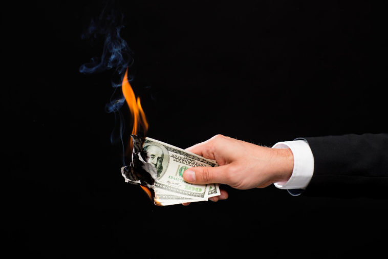 hand holding burning dollar bills