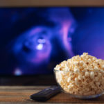glass bowl with popcorn in front of a working tv