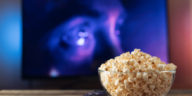 glass bowl with popcorn in front of a working tv