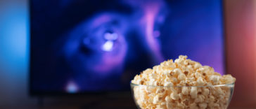 glass bowl with popcorn in front of a working tv