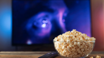 glass bowl with popcorn in front of a working tv