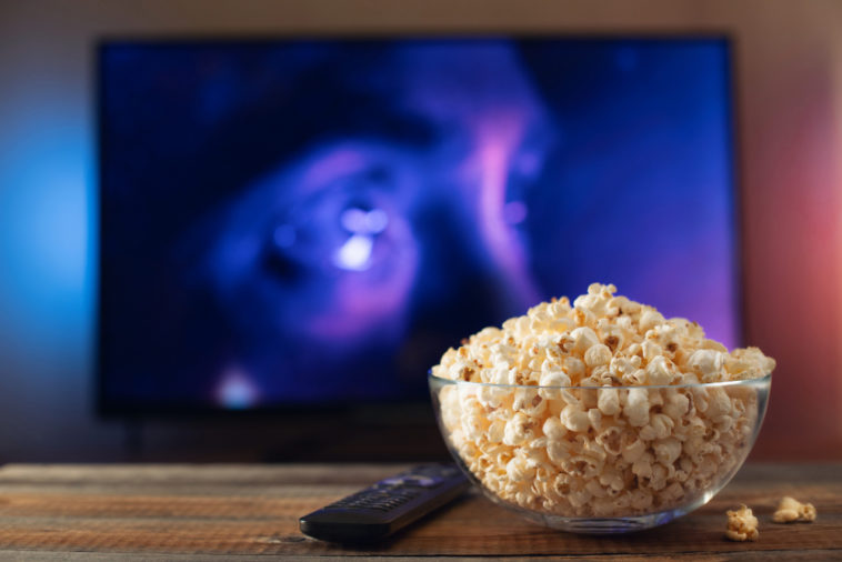 glass bowl with popcorn in front of a working tv