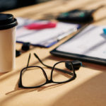 office table with glasses, papers with marker and coffee cupr