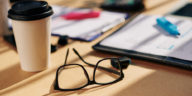 office table with glasses, papers with marker and coffee cupr
