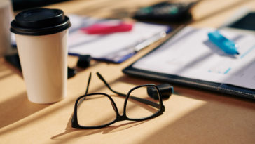 office table with glasses, papers with marker and coffee cupr