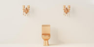 gold toilet bowl in front of a cream color wall