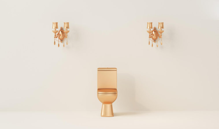 gold toilet bowl in front of a cream color wall