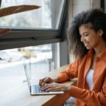 woman sitting at a table typing on a laptop