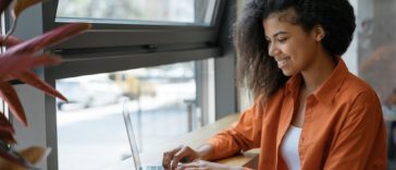 woman sitting at a table typing on a laptop