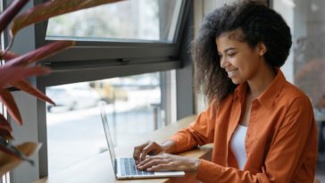 woman sitting at a table typing on a laptop