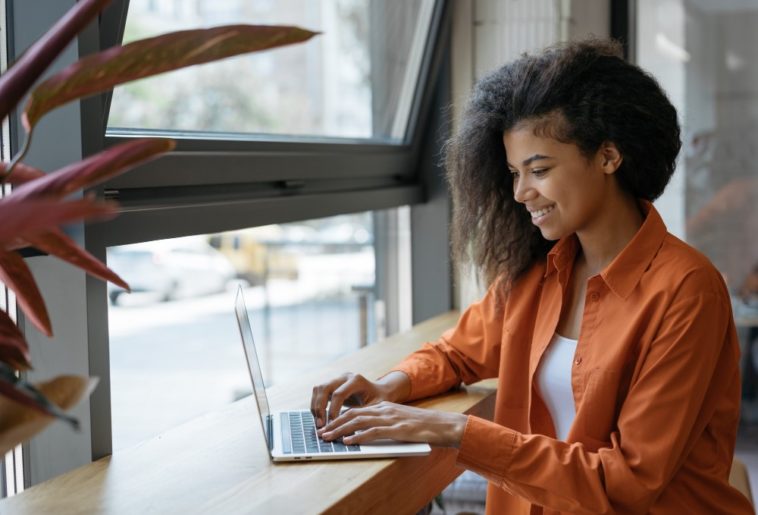 woman sitting at a table typing on a laptop