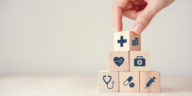 a hand stacking wood cubes with medical icons on them