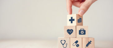 a hand stacking wood cubes with medical icons on them