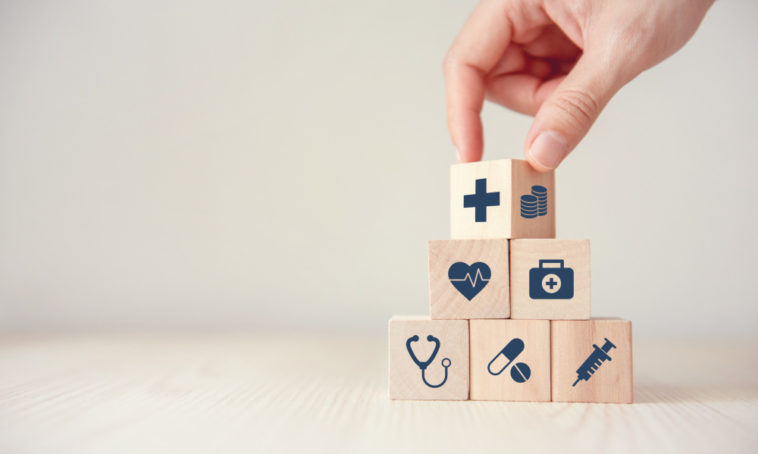 a hand stacking wood cubes with medical icons on them