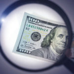 magnifying glass over a hundred dollar bill