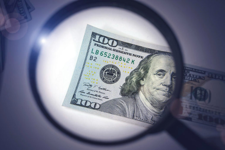 magnifying glass over a hundred dollar bill