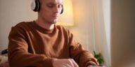 man typing with a headset on his head