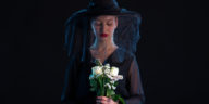 mournful woman dressed in black holding white roses