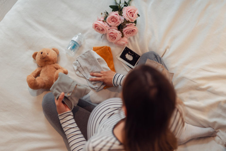 pregnant woman folding baby clothes