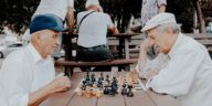 senior men playing chess in park
