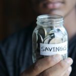 woman holding jar of coins labelled "savings"