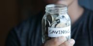 woman holding jar of coins labelled "savings"