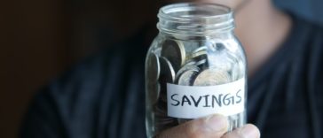 woman holding jar of coins labelled "savings"