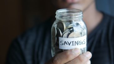 woman holding jar of coins labelled "savings"