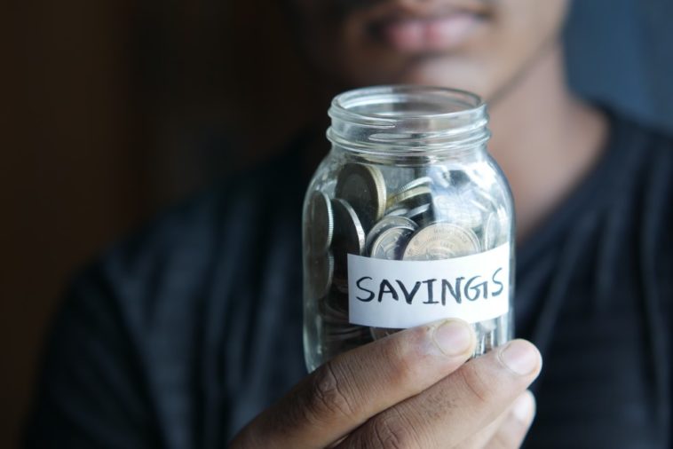 woman holding jar of coins labelled "savings"