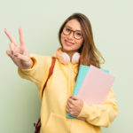 student smiling and gesturing the peace sign