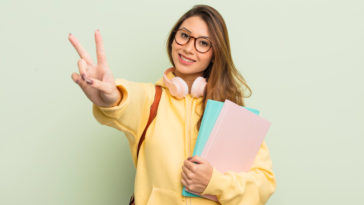 student smiling and gesturing the peace sign