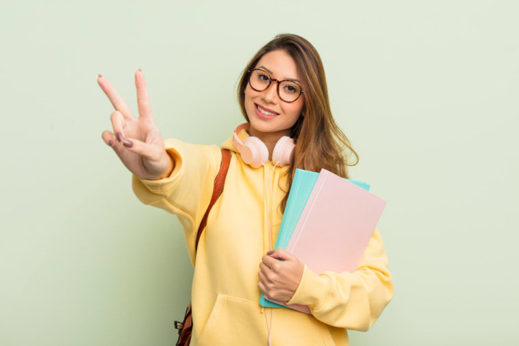 student smiling and gesturing the peace sign