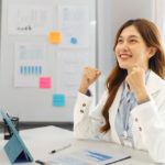 businesswoman in office raising arms to celebrate